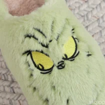 Gros plan sur le visage brodé du Chausson Grinch